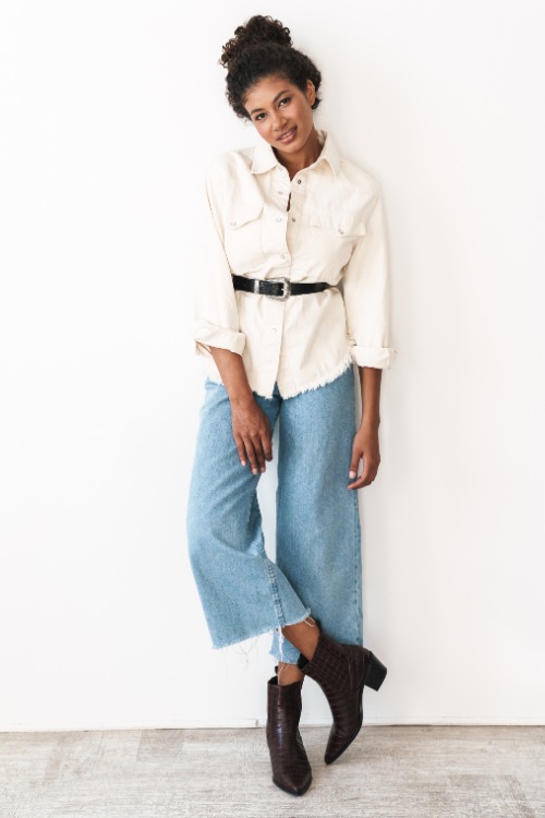 a woman wears cowboy boots with flare jeans and a white shirt