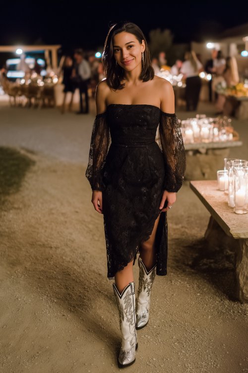 A woman in a black lace midi dress with sheer sleeves and white cowboy boots with silver embroidery