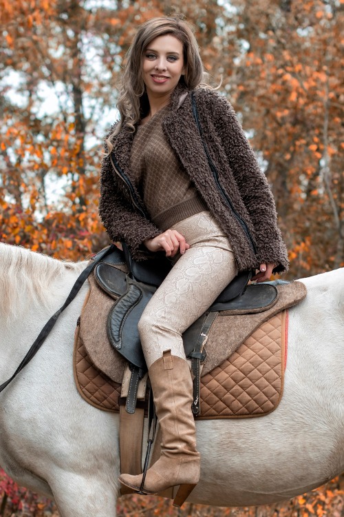A woman wears cowboy boots with leggings, fur coat and a knitted top