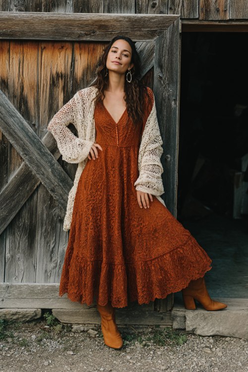 A woman wears a cinnamon-colored lace dress with sheer long sleeves, a flared skirt, and a crochet bodice, styled with block-heeled booties