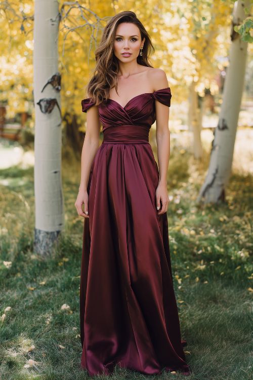 a woman wearing a burgundy off shoulder fall wedding guest dress with a full skirt