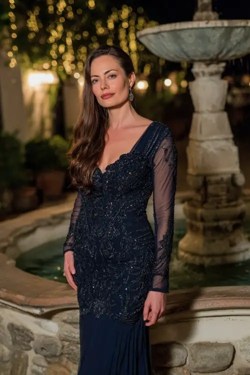 a woman over 50 in a navy chiffon gown with sheer long sleeves and intricate beadwork