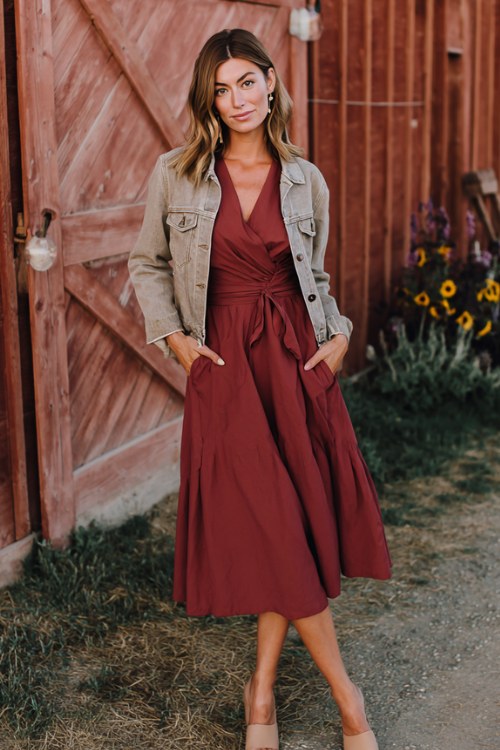 A woman wears a burgundy wrap midi dress with long sleeves, paired with a light-wash jean jacket and tan block heels