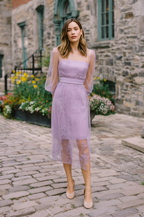 A woman over 50 wears a soft lilac tea-length dress with sheer embroidered long sleeves