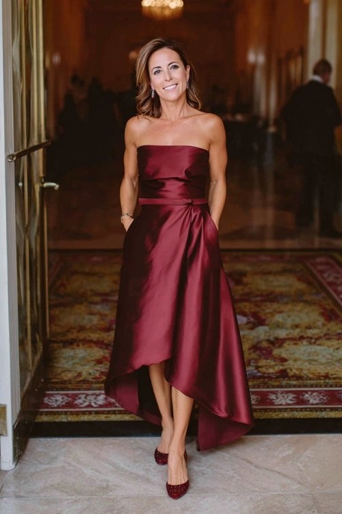a woman over 50 in a burgundy satin high-low hem gown with subtle pleating and thin belt (2)