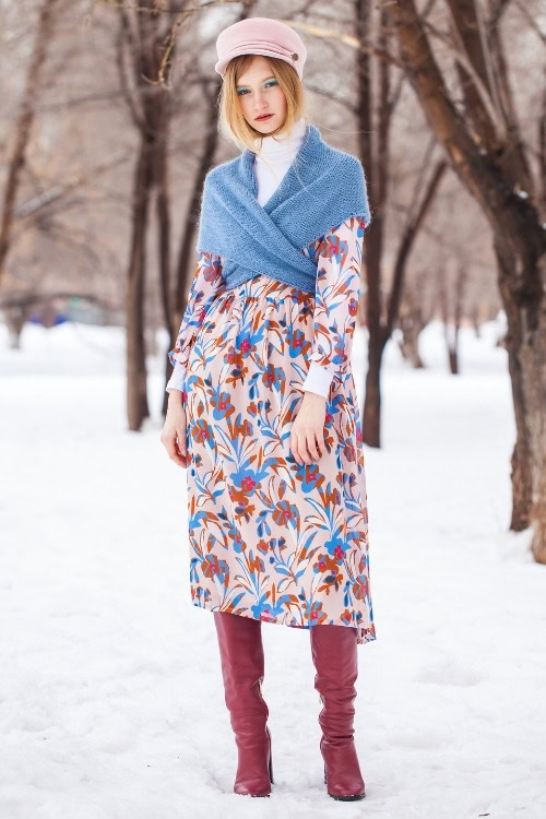 a woman wears red cowboy boots with a pattern dress for winter