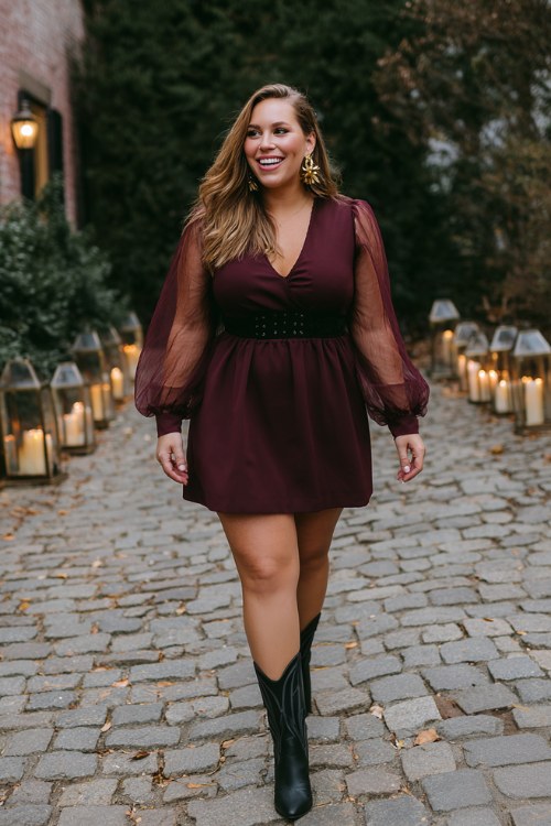 A plus-size woman wears a burgundy A-line dress with sheer long sleeves and short black cowboy boots