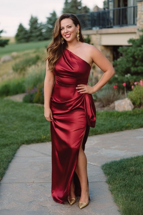 A curvy woman wears a deep red satin gown with a one-shoulder draped detail (2)