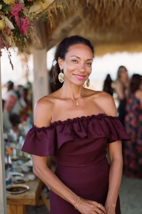 a woman over 50 in a deep wine off-shoulder midi dress with a ruffled hem