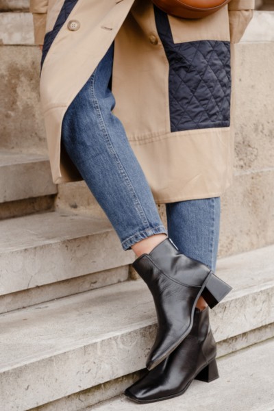 A woman wears black cowboy boots with jeans and blazer