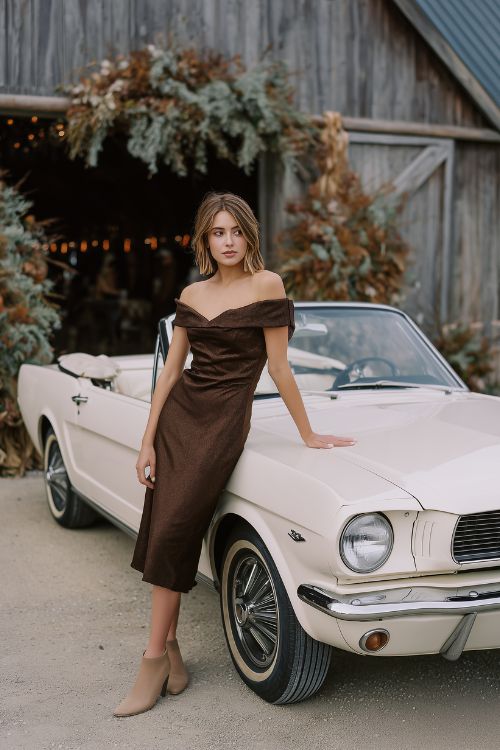 A woman wears a chocolate brown off-the-shoulder dress with a subtle shimmer