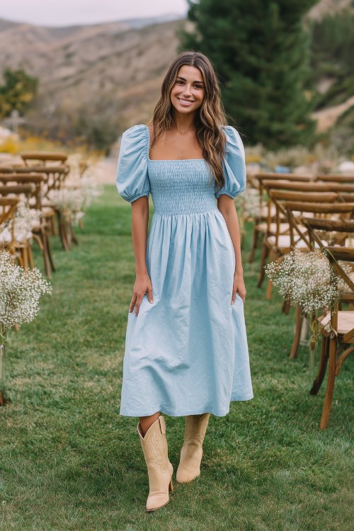 A petite woman wears a sky-blue smocked maxi dress with puff sleeves and a square neckline, paired with light tan cowboy boots