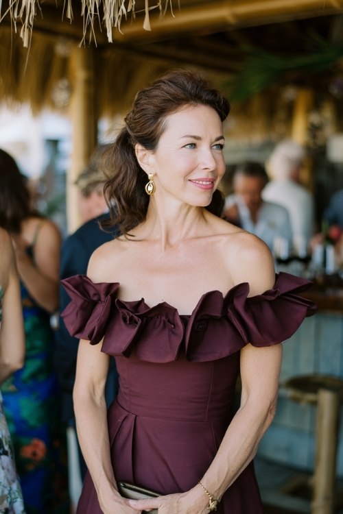 a woman over 50 in a deep wine off-shoulder midi dress with ruffle details
