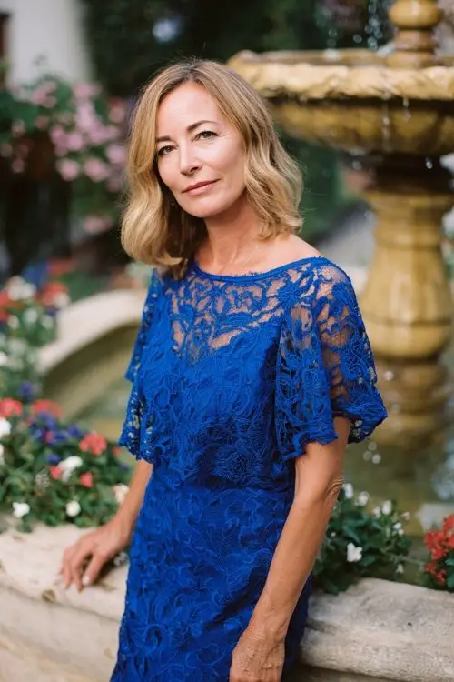 a woman over 50 in a royal blue lace overlay cocktail dress with flutter sleeves