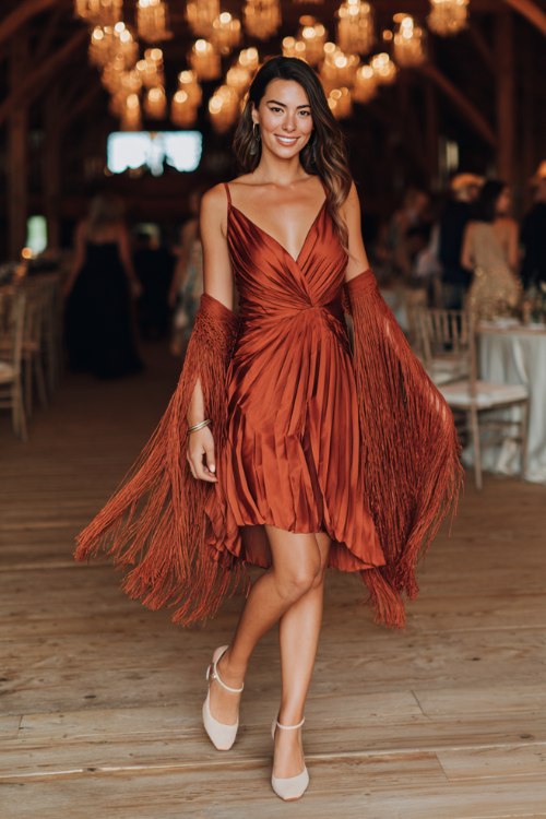 A woman wears a rust micro-pleat midi with a wrap front and fringe shawl