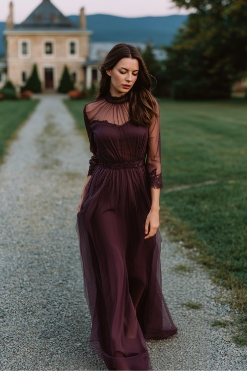 A woman in a plum gown with a sheer high neckline, mesh sleeves, and delicate lace trim