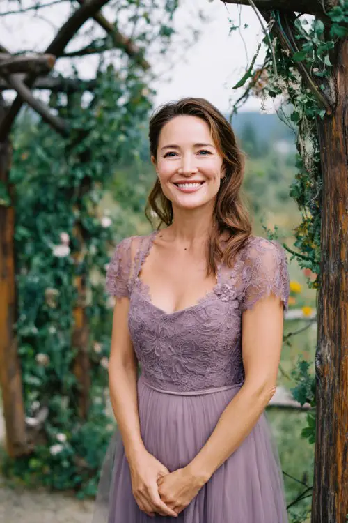 A woman over 50 wears a lavender midi dress with lace cap sleeves and a tulle skirt