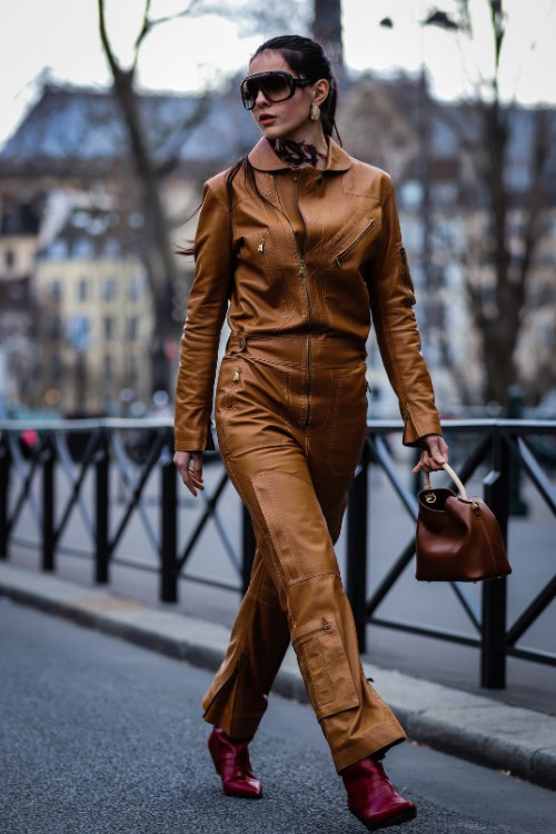 A woman wears cowboy boots with a leather jumpsuit