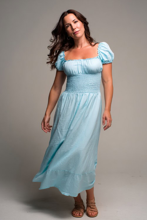 A mid-size woman in a smocked maxi dress with short sleeves and flat sandals, styled for a relaxed but polished summer look, simple studio background