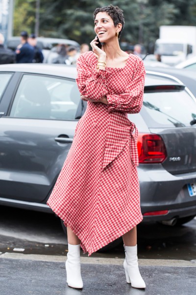 A woman wears white cowboy boots with a plaid pink dress