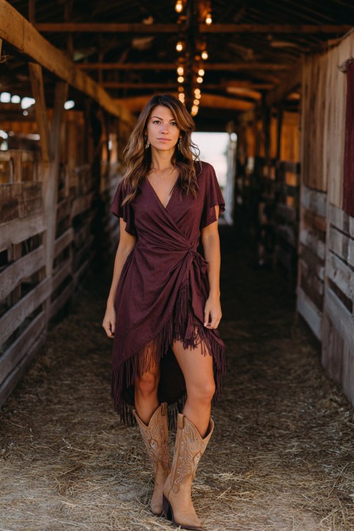 A woman wears a plum wrap dress with a high-low hem and tan cowboy boots