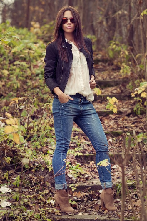 A woman wears ankle cowboy boots with jeans, white top and a coat