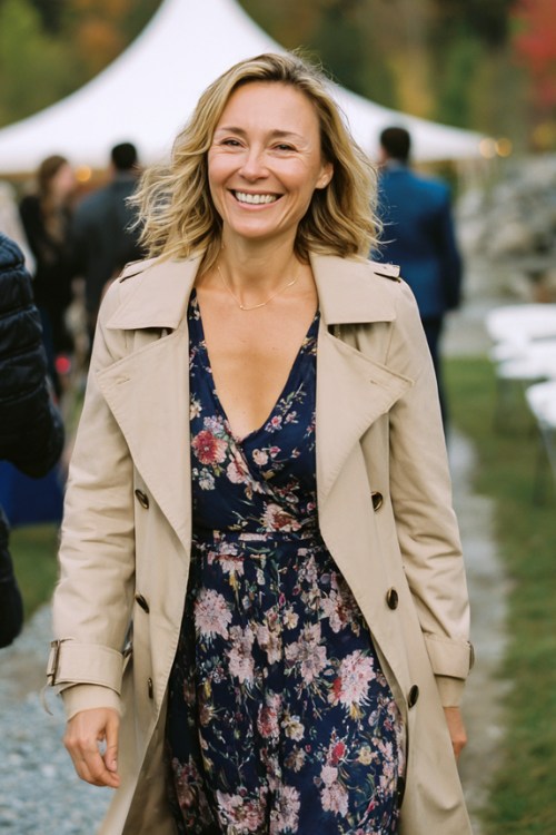 A woman over 40 wears a navy floral long-sleeve dress with a beige trench coat