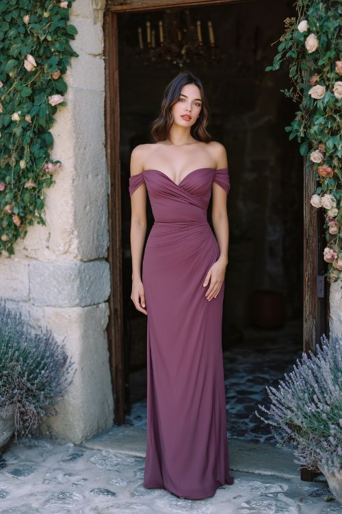 A woman wears a wine-colored off-the-shoulder gown with a softly draped neckline