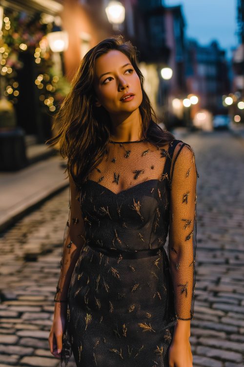 A petite woman wears a charcoal sheer overlay dress with metallic leaf motifs and a fitted slip beneath