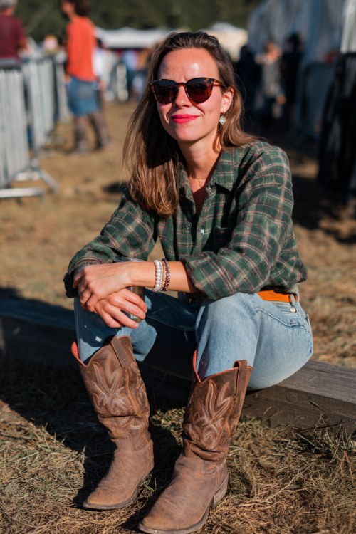 A woman wears straight-leg jeans with a forest green flannel tucked into a belt, accessorized with brown cowboy boots (2)