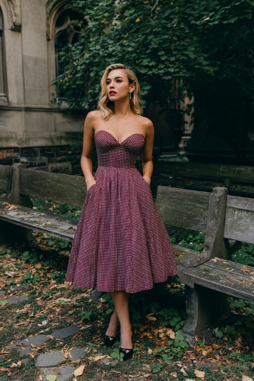 A woman wears a berry micro-check fit-and-flare midi with a sweetheart neckline and pockets, styled with black Mary Jane heels