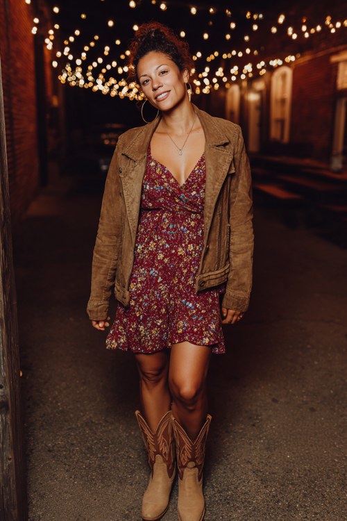 A woman over 30 wears a burgundy floral wrap dress with long sleeves, paired with tan cowboy boots and a suede jacket