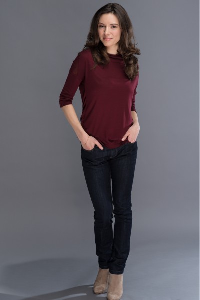 A woman wears brown cowboy boots, dark jeans and long sleeves sweater