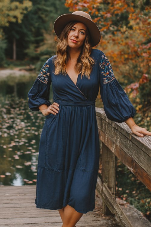 A curvy woman wears a navy boho midi dress with floral patchwork and peasant sleeves