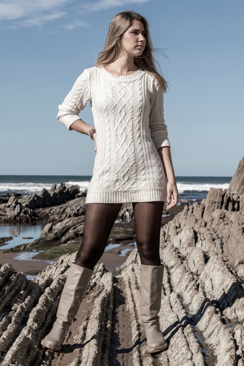 A woman wears grey cowboy boots with a sweater dress