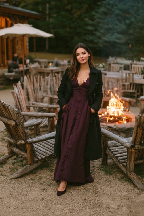 A woman wears a long plum dress with lace sleeves, dark coat, and pointed heels