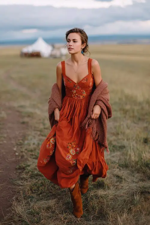 A petite woman in a full-body rust A-line dress with embroidered florals and a structured bodice, paired with suede booties