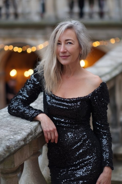 a woman over 50 in a black sequin bateau-neck cocktail dress with long sleeves
