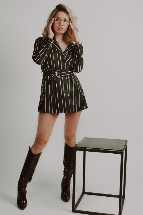 a woman wears black cowboy boots with a striped wrap dress