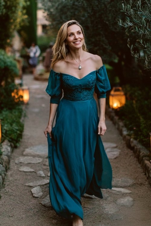 a woman over 50 in a teal chiffon gown with embroidered bodice and flowy skirt