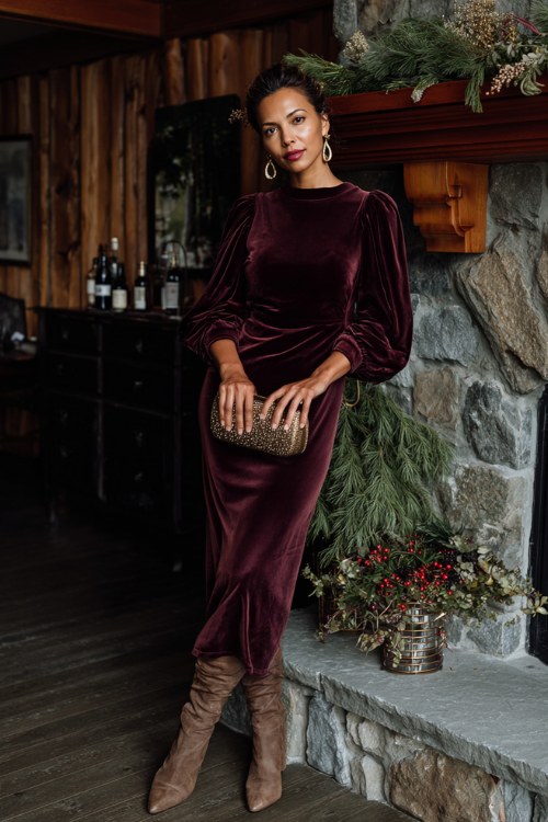 A woman over 30 wears a deep wine velvet gown with puff sleeves, paired with tall suede boots