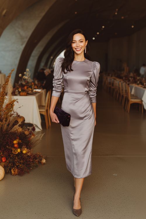 A full-body image of a woman in a cool lavender-gray satin midi dress with pleated paneling and structured shoulders (1)