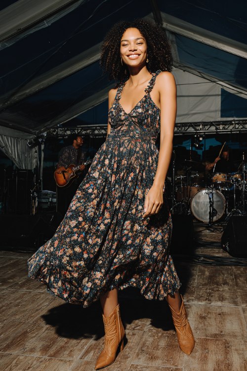 A woman wears a midnight floral cottage-garden midi with a smocked bodice, ruffled straps