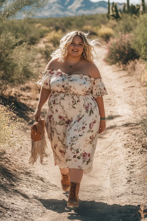 A plus-size woman in a flowy off-the-shoulder floral maxi dress with puff sleeves, styled with a fringe crossbody bag and suede ankle boots, walking through a dusty Coachella trail