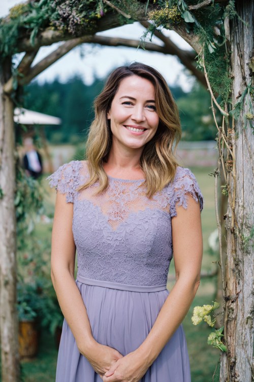A woman over 50 wears a lavender midi dress with lace cap sleeves and a tulle skirt