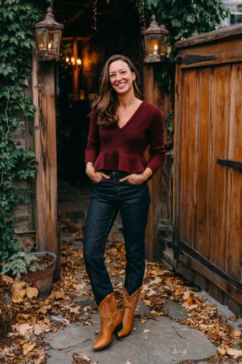 A woman wears dark-wash jeans, a burgundy peplum sweater, and caramel-colored cowboy boots