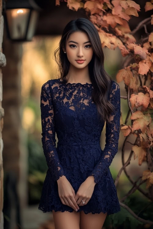 A woman wears a navy blue lace wedding guest dress with long sleeves and a high neckline