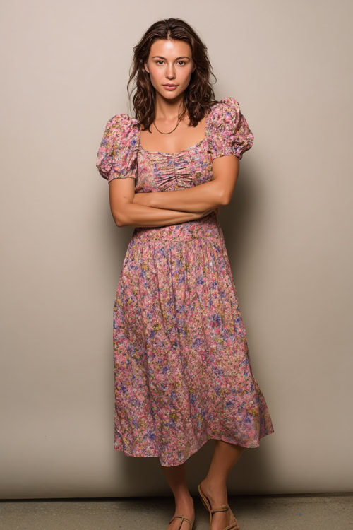 A woman in a flowy floral midi dress with short puff sleeves and flat sandals, styled for a relaxed summer outing, simple studio background