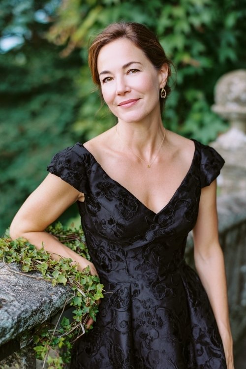 a woman over 50 in a black jacquard tea-length dress with subtle floral pattern and cap sleeves