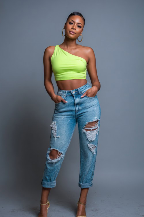 A Black woman in a neon green one-shoulder crop top with ripped denim jeans and heeled sandals, styled for a trendy and vibrant summer night out